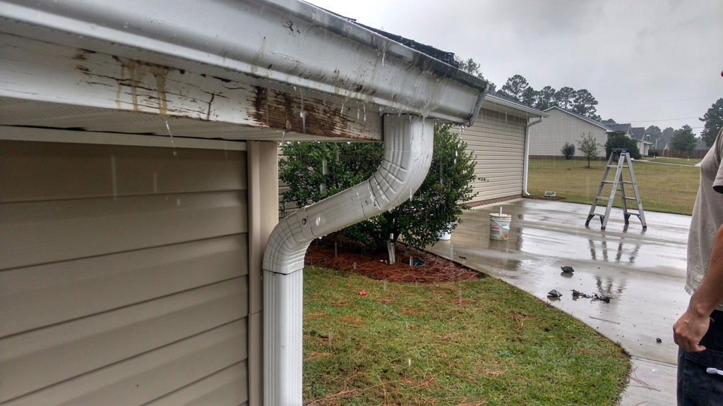 Rainwater overflowing from a residential gutter during a storm