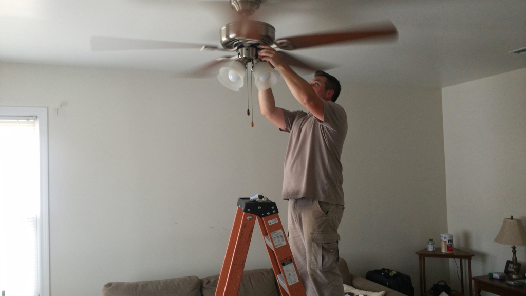 Ceiling fan with a slight wobble being inspected in a residential room