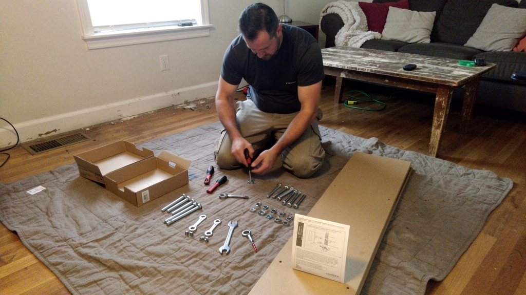 Handyman assembling a flat-pack furniture piece with organized hardware