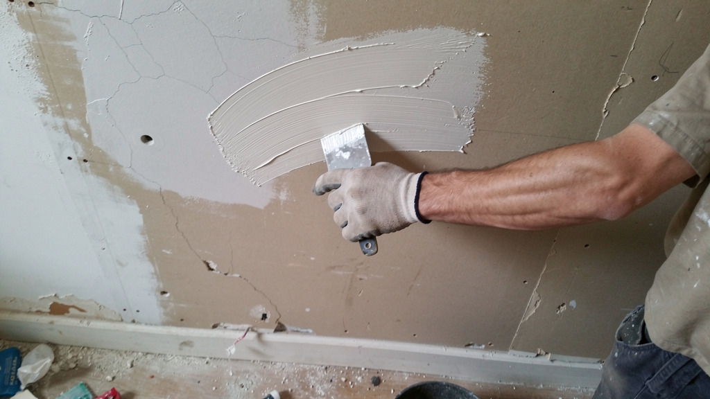 Close-up of a wallboard repair being feathered smooth before painting